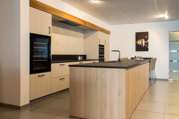 Keukenontwerp met natuurlijke houttinten – Tijdloos keukenontwerp met een zwart werkblad en lichte houten fronten.
