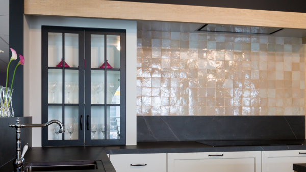 Landelijke keuken met warme houten kasten en authentieke handgrepen, mozaïeken spatwand, witte kasten en een ingebouwde vitri